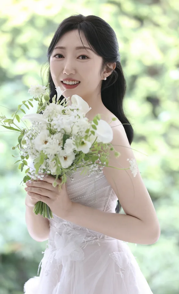 흰 꽃다발을 들고 미소 짓는 신부