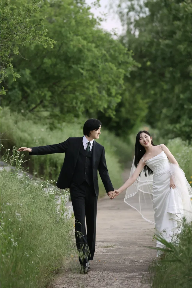 초록빛 산책길에서 손을 잡고 걷는 신랑과 신부