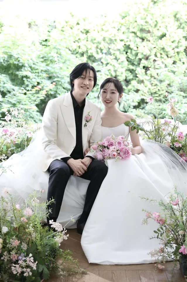 꽃 사이에 나란히 앉아 있는 신랑과 신부